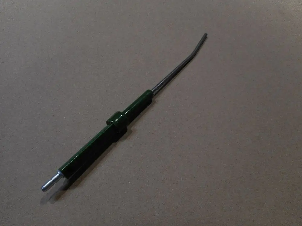Elektrode von Remeha in länglicher Form mit einem grünen Kunststoffgriff und einem metallischen Ende, auf einem neutralen Untergrund platziert.